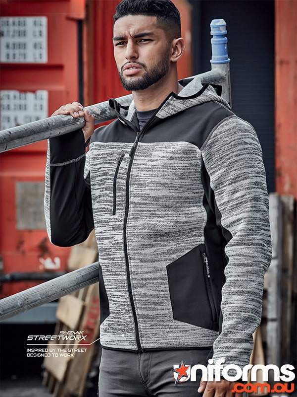 A man in a grey and black Syzmic Streetworx Reinforced Knit Hoodie style ZT360 leans against a wall.